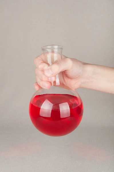 Líquido rojo dentro del frasco de laboratorio en mano sobre fondo blanco — Foto de Stock