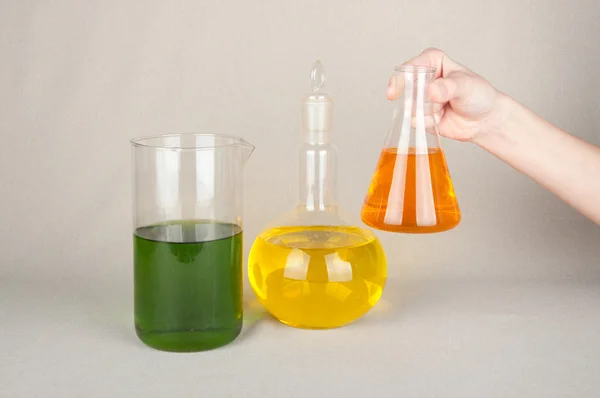 Botellas de laboratorio con líquido de color en la mano — Foto de Stock