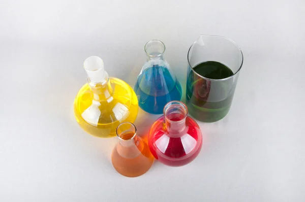 Frascos de laboratorio con líquido de color sobre fondo blanco — Foto de Stock