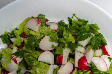 Beyaz tabakta taze bahar salatası. Yeşil, koyu yapraklı, turp gibi yakın plan. Vejetaryen yemeği, vitamin kasesi. Kilo verme diyeti. Yüksek kalite fotoğraf