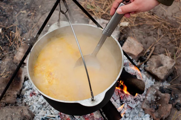 Cooking porridge in a casserole on the fire — Stock Photo, Image