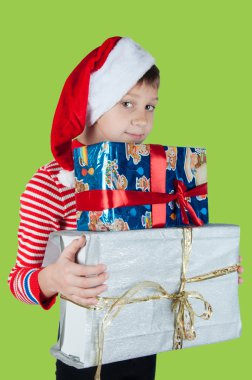 Noel Baba şapkalı kutuları yeşil arka plan üzerinde tutan şirin çocuk