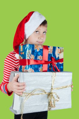 Noel Baba şapkalı kutuları yeşil arka plan üzerinde tutan şirin çocuk