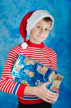 Mavi kutu tutan Santa şapkalı çocuk gülümseyen