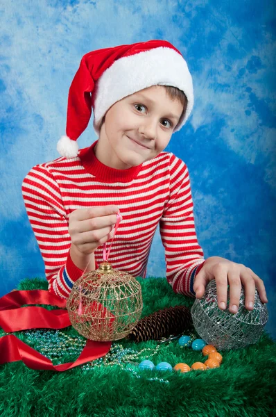 Criança sorridente em chapéu de Papai Noel no fundo azul — Fotografia de Stock