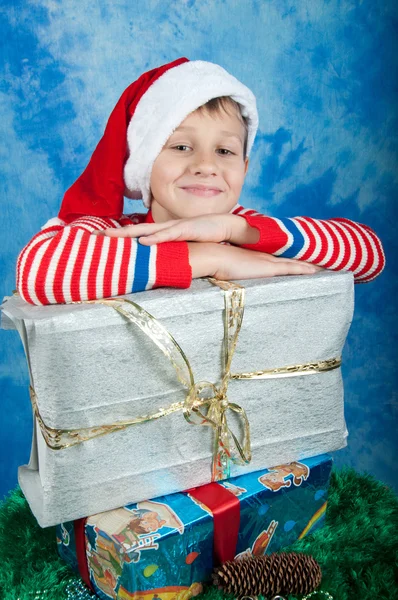 Garçon souriant dans Santa hatlaying sur cadeaux de Noël — Photo