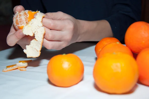 Kinderhände reinigen Mandarine auf weißem Tisch — Stockfoto