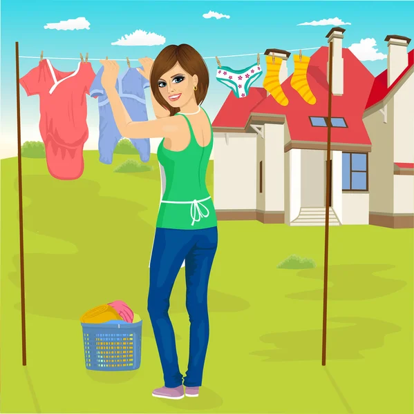 Молодая женщина вешает мокрую одежду сушиться рядом с домом семьи — стоковый вектор
