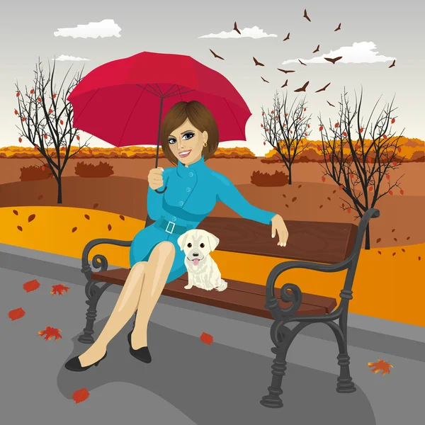 年轻女子在蓝色大衣打着红伞与拉布拉多小狗在城市公园的长椅上坐在一个下雨天 — 图库矢量图片