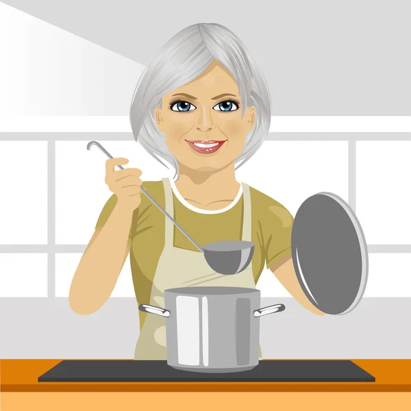 Sorrindo mulher madura com concha de sopa de cozinha na panela na cozinha doméstica —  Vetores de Stock