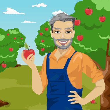 meyve bahçesinde bir elma tutan olgun çiftçi adam