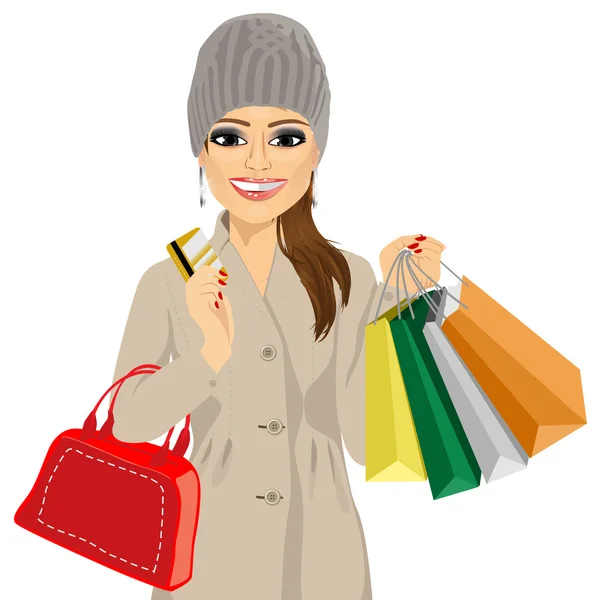 Mujer en un abrigo de invierno y sombrero de punto con bolsas de compras y su tarjeta de crédito — Vector de stock