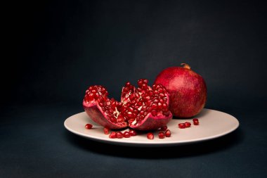 Koyu arkaplanda, tabakta kırmızı nar.