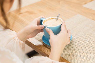 Bir kızın ellerinde güzel bir fincan kahve.