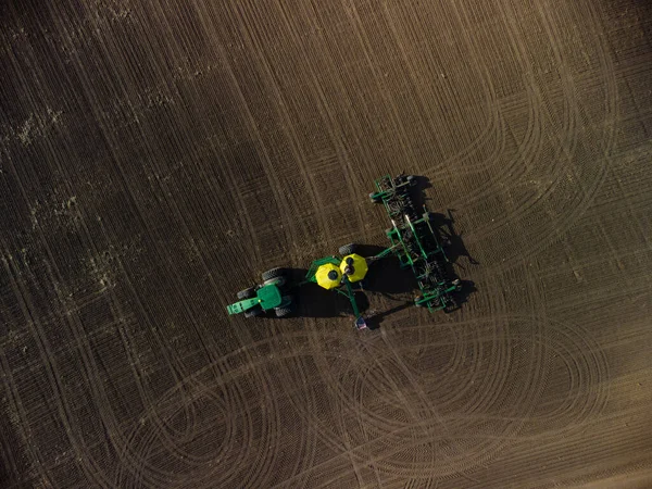Зелений трактор з посівним комплексом у полі зору зверху — стокове фото