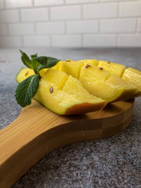 Tahta kesme tahtasında naneli mango dilimleri.