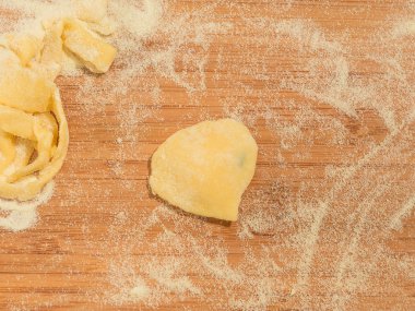 Kalp şeklinde ev yapımı raviolo un serpilir ve ahşap bir masa yerleştirilen.