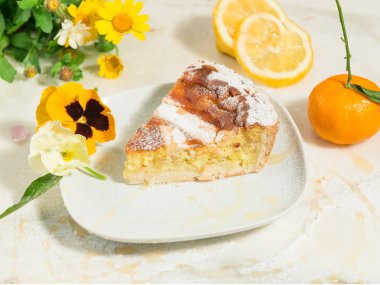 A piece of Neapolitan Easter pie sprinkled with icing sugar and decorated with pansy,spring flowers and fresh fruits. clipart