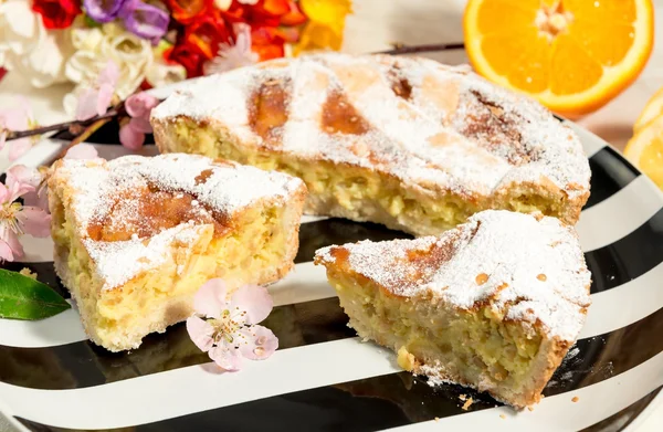 Napoliten Paskalya turta ile krema şeker serpilir ve badem çiçeği, Frezya ve taze meyve ile dekore edilmiş.