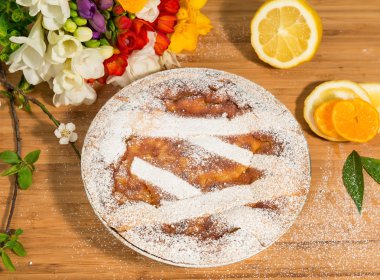 Napoliten Paskalya Pasta krema şeker serpilir ve Frezya ve taze meyve ile dekore edilmiş.