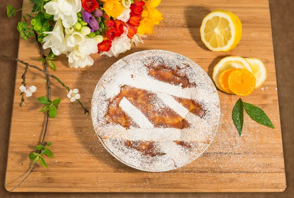 Napoliten Paskalya Pasta krema şeker serpilir ve Frezya ve taze meyve ile dekore edilmiş.