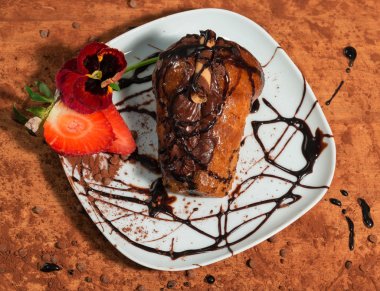 Napoliten tatlı çikolata krema, taze çilek, Hercai Menekşe ve kakao ile dekore edilmiş toz.