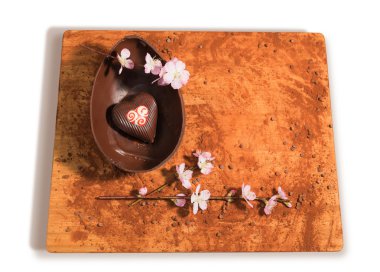 Easter chocolate egg with a surprise of a heart decorated,sprinkled with cocoa powder,chocolate chips and almond blossom. clipart