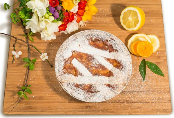Napoliten Paskalya Pasta krema şeker serpilir ve Frezya ve taze meyve ile dekore edilmiş.