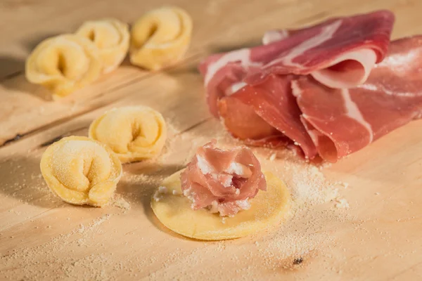 Olasz házi tortellini, nyitott és zárt, tele prosciutto di Parma, a fa ország asztalra. — Stock Fotó