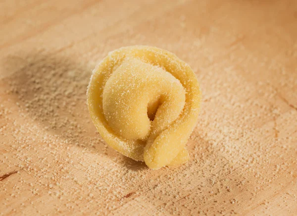 Італійські домашні tortellino розміщені на дерев'яні ftable посипану борошном. — стокове фото