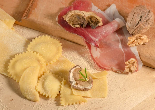 Pasta cruda fatta a mano e ravioli fatti in casa italiani, aperti e chiusi, ripieni di prosciutto di parma, erbe aromatiche e funghi secchi . — Foto Stock