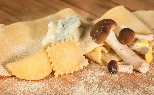 Ravióli caseiro italiano com queijo gorgonzola e cogumelos frescos, colocado sobre uma mesa de madeira e polvilhado com farinha . — Fotografia de Stock