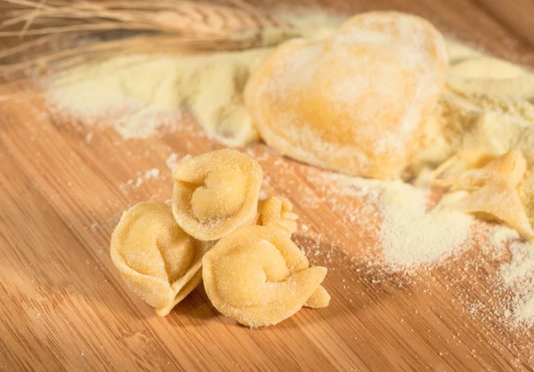 Italienische hausgemachte Tortellini mit Mehl, rohem Teig, Weizenähre und herzförmigen Ravioli. — Stockfoto