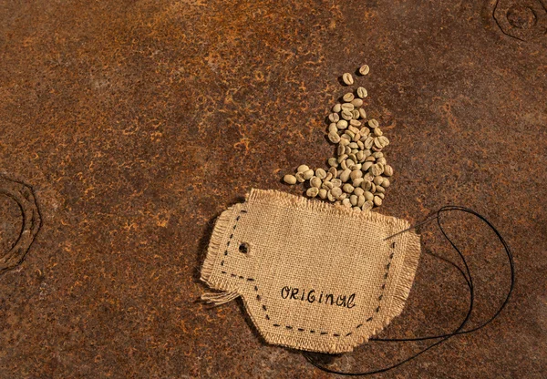 Una taza cosida en yute con aguja y alambre lleno de granos de café crudos colocados en la mesa oxidada . —  Fotos de Stock