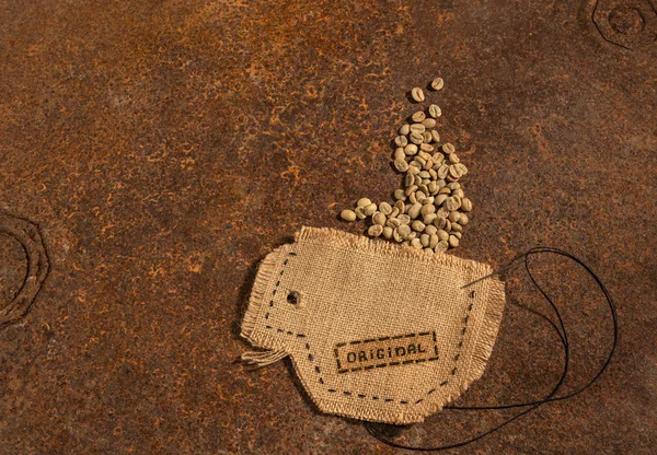 Una taza cosida en yute con aguja y alambre lleno de granos de café crudos colocados en la mesa oxidada . —  Fotos de Stock