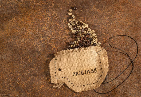 Une tasse cousue en jute avec aiguille et fil plein de grains de café placés sur une table rouillée . — Photo