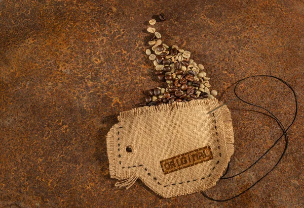 Uma xícara costurada em juta com agulha e arame cheio de grãos de café colocados na mesa enferrujada . — Fotografia de Stock