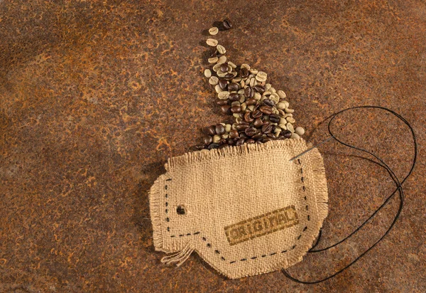 Pohár, šitá v juta s jehlou a drát plný kávová zrna na rezavý stůl. — Stock fotografie