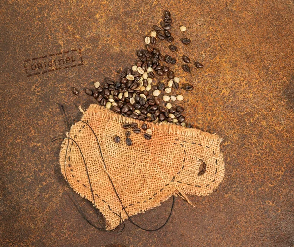 Une tasse cousue en jute avec des grains de café placés sur une texture rouillée . — Photo