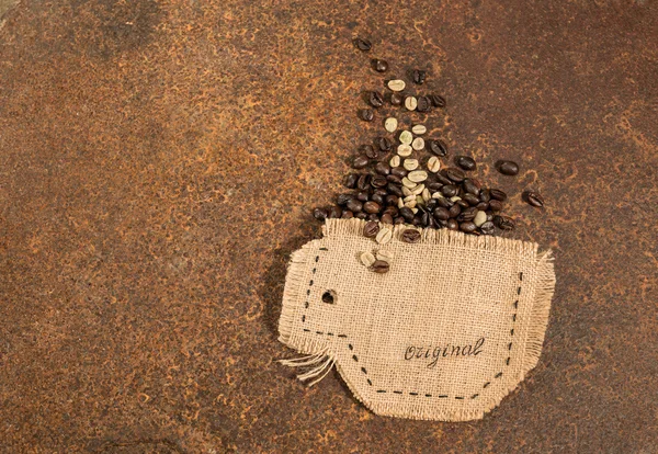 Uma xícara costurada em juta com grãos de café colocados em textura enferrujada . — Fotografia de Stock