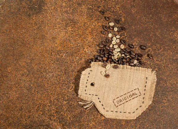 A cup sewn in jute with coffee beans placed on rusty texture. — Zdjęcie stockowe