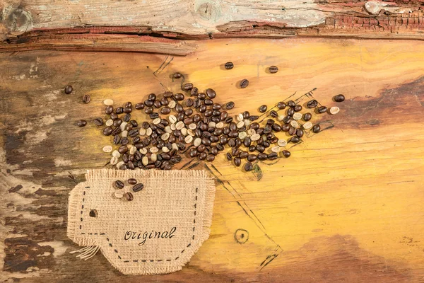 Une tasse cousue en jute avec des grains de café placés sur une vieille table en bois . — Photo
