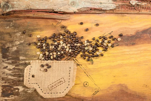 Чашка, зшита в джуті з кавовими зернами, розміщена на старому дерев'яному столі . — стокове фото