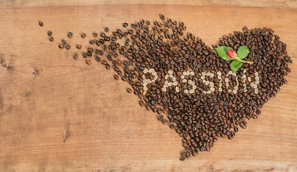 Ein Herz aus Kaffeebohnen mit roter Knospe. — Stockfoto
