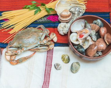 Yengeç, deniz mahsulleri spagetti ve etnik kumaş üzerine kabukları ile.