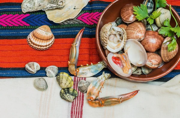 Mariscos con garras de cangrejo y conchas dispuestas sobre tela Etnic . —  Fotos de Stock