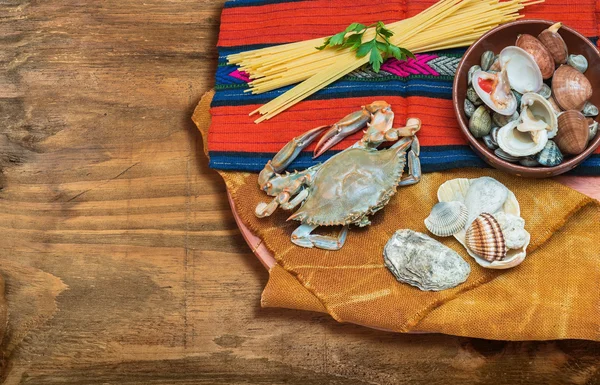 Cangrejo, mariscos con espaguetis y conchas sobre tela étnica . —  Fotos de Stock