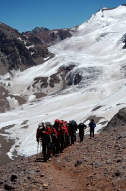 Karlı ve sarp dağlarda sıra sıra dağcıların aşırı koşullardaki hareketleri.