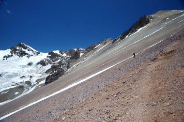 Yalnız bir dağcı kışın karlı dağlarda bir yamaca tırmanır. Dağlarda fotoğrafçı.