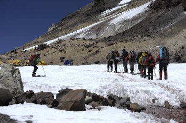 Tırmanışçılar dağın eteğinde kurulmuş bir çadır kampının etrafında kayak yapıyorlar..